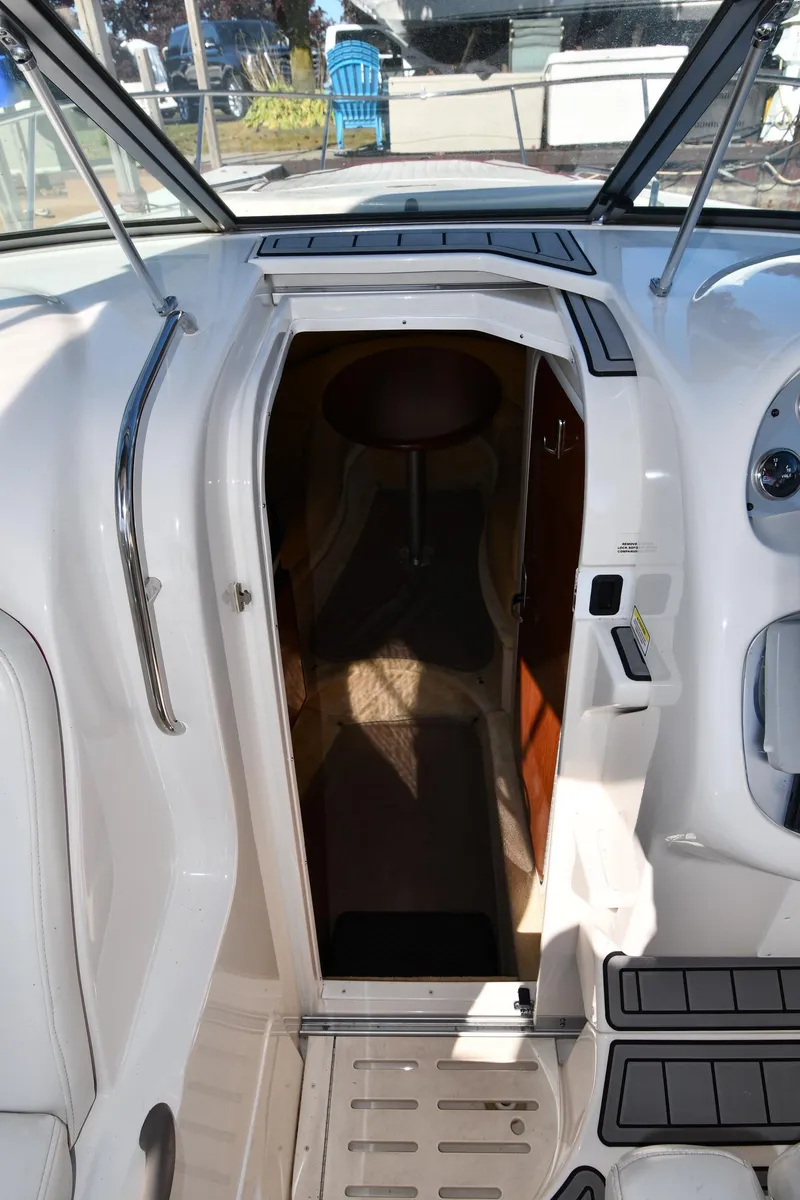 Slide: The Image of 2006 Monterey 298SC Super Sport boat interior with cushioned seating, docked by calm waters. - 33