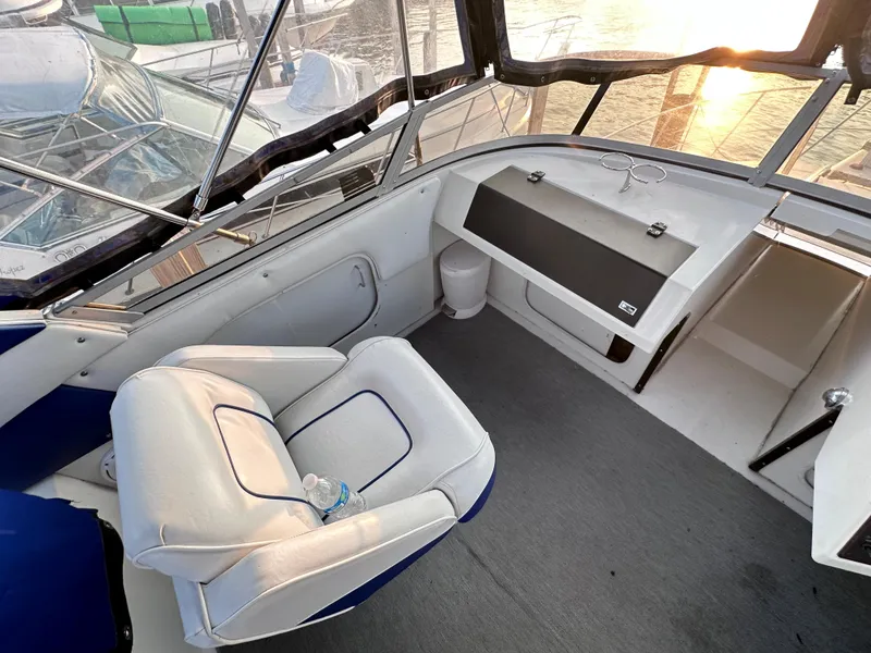 Slide: The Image of 1994 Carver 340 Santego boat interior with white seating and helm, sunset view. - 11