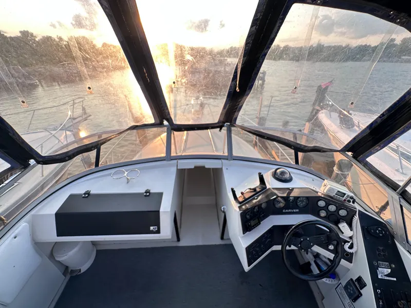 Slide: The Image of 1994 Carver 340 Santego boat interior with helm, steering wheel, and sunset view. - 3