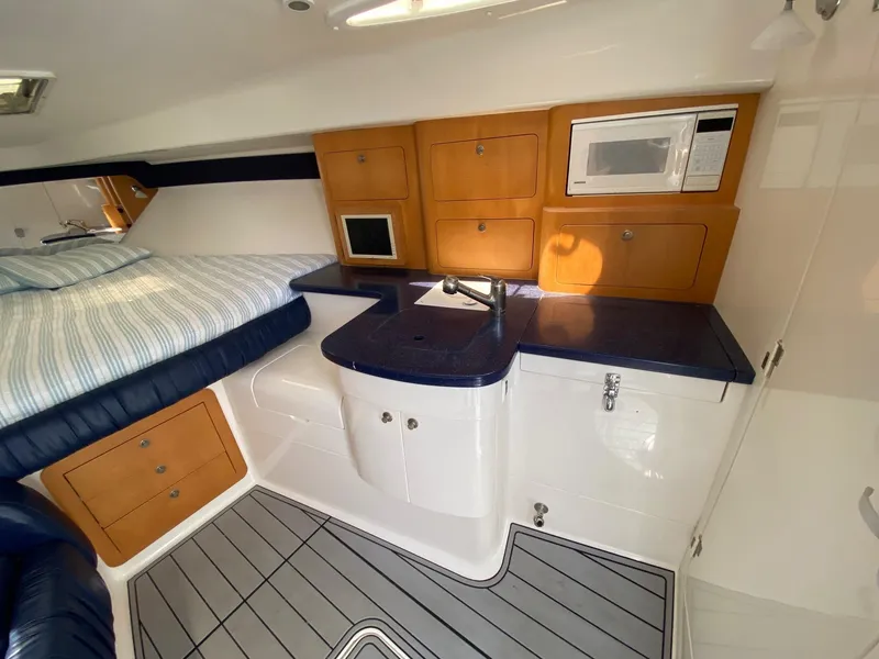 Slide: The Image of 2001 Intrepid 377 Walkaround cabin with bed, kitchenette, and storage cabinets. - 34