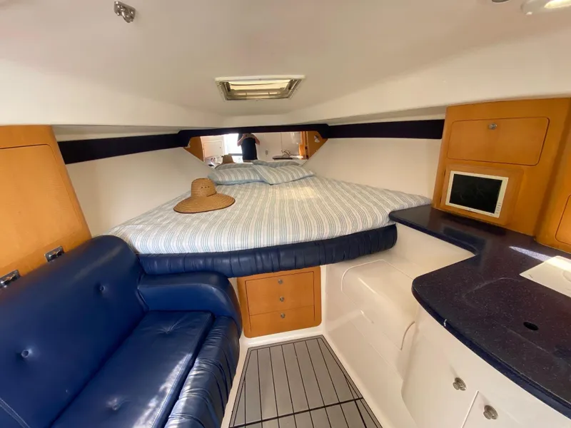 Slide: The Image of 2001 Intrepid 377 Walkaround cabin interior with bed, blue seating, and kitchenette. - 35