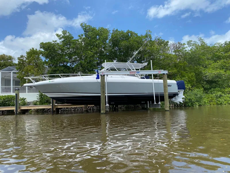 Slide: The Image of 2001 Intrepid 377 Walkaround boat docked by lush greenery and calm water. - 4