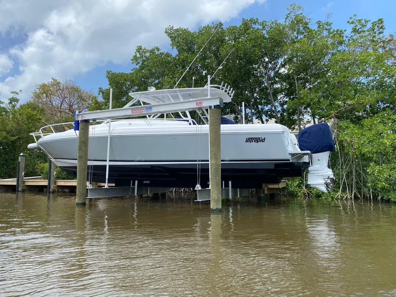 Slide: The Image of 2001 Intrepid 377 Walkaround boat on lift by water, surrounded by trees. - 8