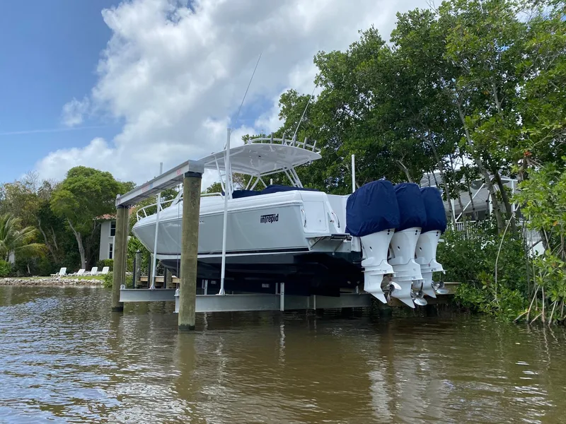 Slide: The Image of 2001 Intrepid 377 Walkaround boat docked with triple outboard engines, surrounded by trees and water. - 9