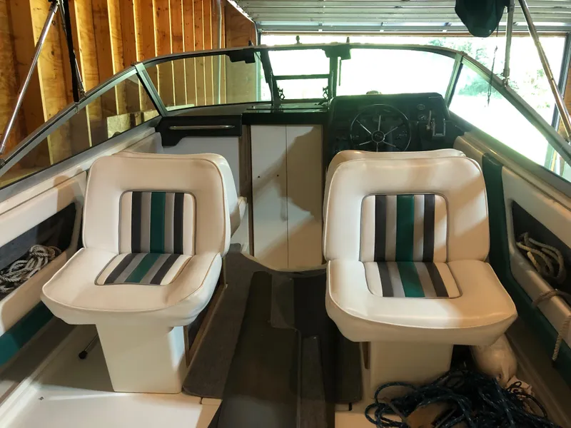 Slide: The Image of 1991 Sea Ray 250 Weekender boat interior with striped seats in a wooden boathouse. - 13