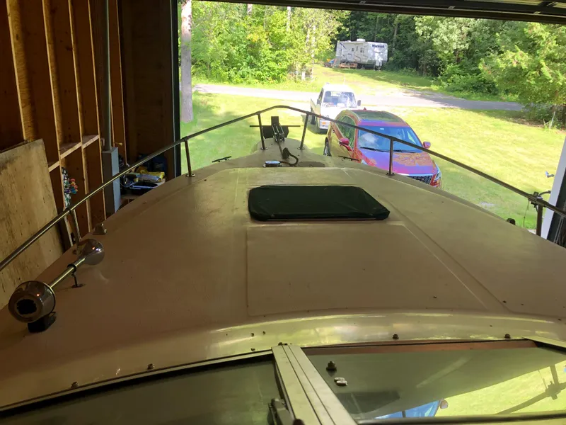 Slide: The Image of 1991 Sea Ray 250 Weekender boat in garage, with cars and greenery outside. - 18