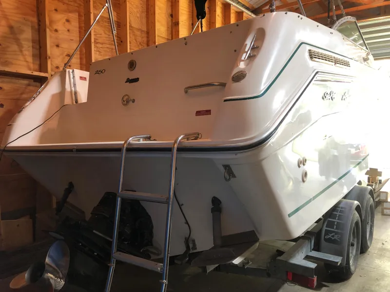 Slide: The Image of 1991 Sea Ray 250 Weekender boat in a garage, rear view with ladder and trailer. - 8