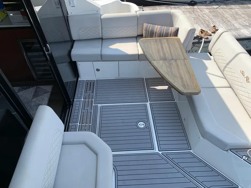 Slide: The Image of 2017 Sea Ray Sundancer 460 yacht cockpit with cushioned seating and wooden table. - 11