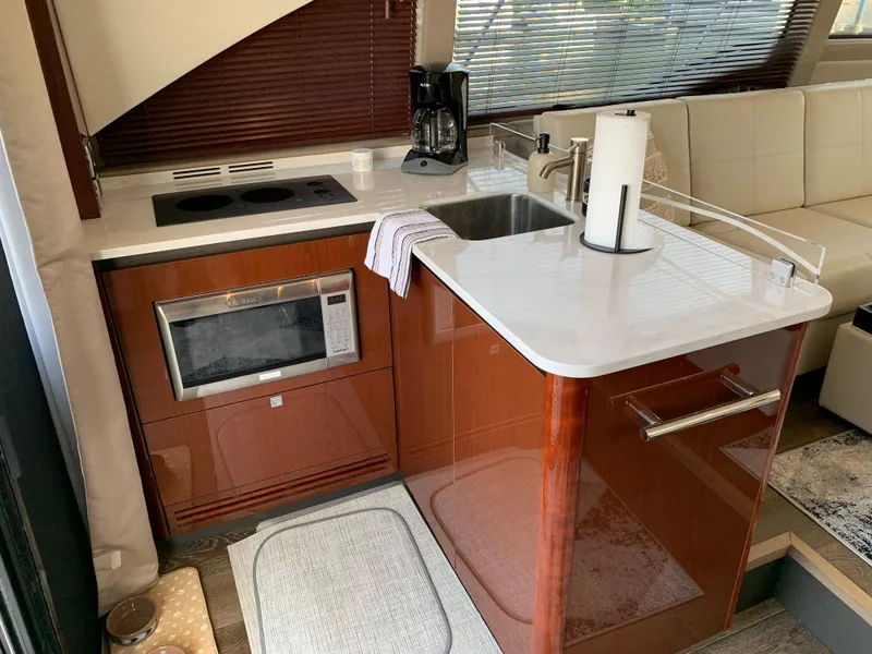 Slide: The Image of 2017 Sea Ray Sundancer 460 yacht kitchen with microwave, sink, and stovetop. - 13