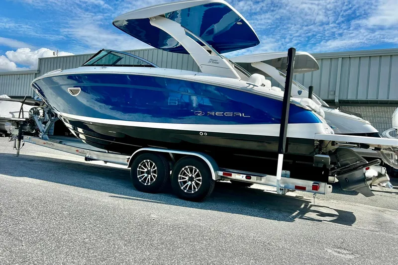 Slide: The Image of 2024 Regal LS9 boat on trailer, blue and white design, parked outdoors. - 3