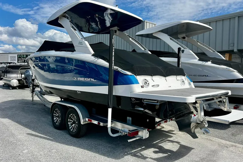 Slide: The Image of 2024 Regal LS9 boat on trailer, blue and white design, parked outdoors. - 6