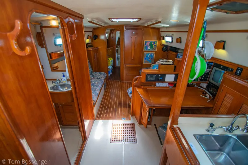 Slide: The Image of Interior of a 1997 Island Packet 45 sailboat, featuring wood finishes and a compact kitchen area. - 7