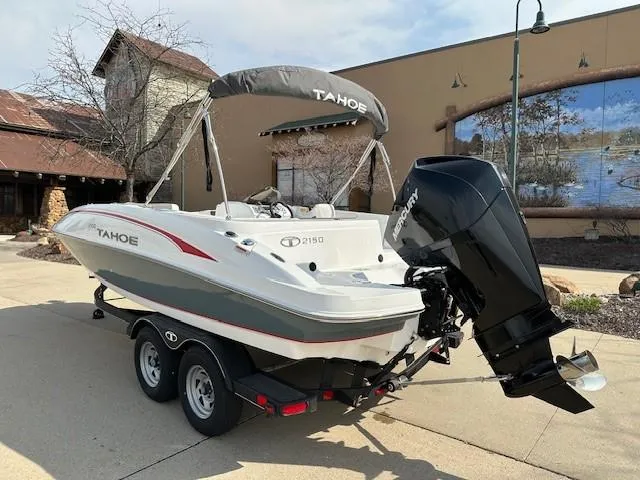 Slide: The Image of 2024 Tahoe 2150 boat on trailer, parked outdoors, featuring sleek design and powerful outboard motor. - 2