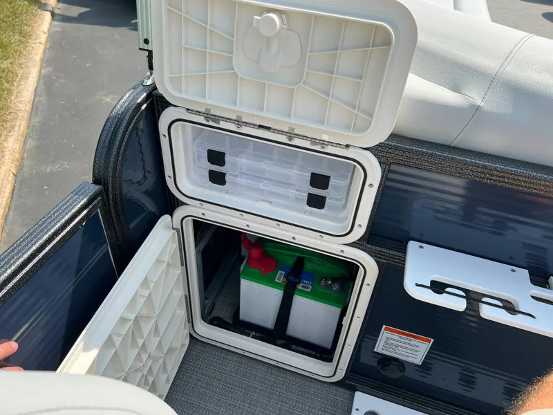 Slide: The Image of 2024 Crest Classic Fish 220 boat storage compartment with battery and seating area. - 14