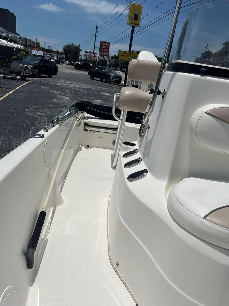 Slide: The Image of 2015 NauticStar 2110 Sport boat interior with seating and console, parked outdoors. - 10