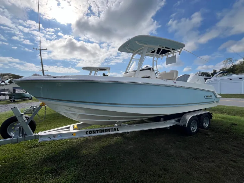 The Image of 2024 Boston Whaler 230 Outrage boat on trailer under a partly cloudy sky. - 0