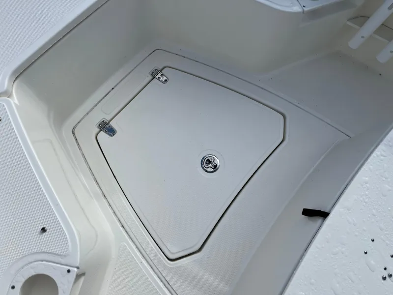 Slide: The Image of 2024 Boston Whaler 230 Outrage storage compartment with secure latch and textured surface. - 12