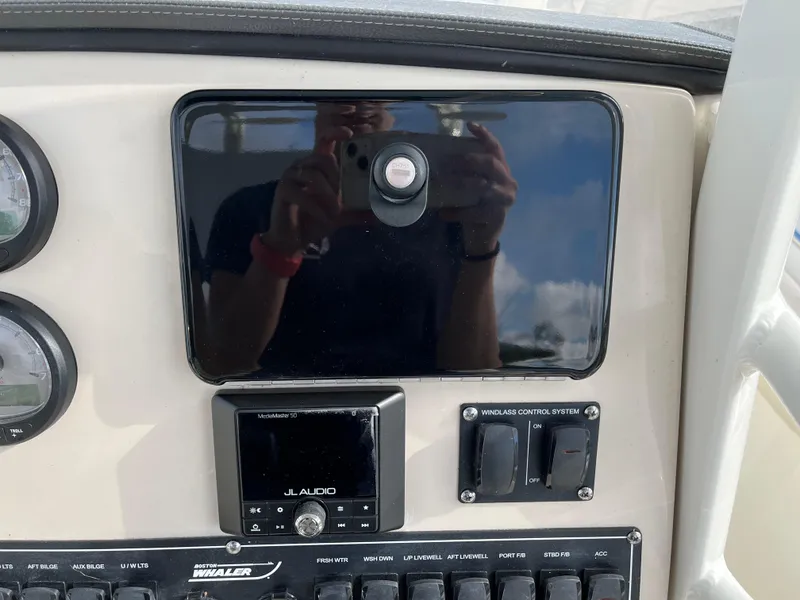 Slide: The Image of 2024 Boston Whaler 230 Outrage dashboard with JL Audio system and control switches. - 17