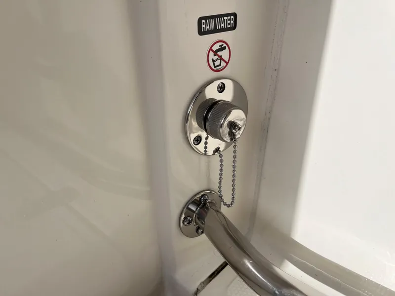 Slide: The Image of 2024 Boston Whaler 230 Outrage raw water inlet with safety warning label. - 20