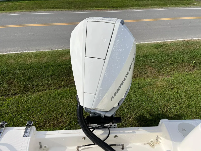 Slide: The Image of 2024 Boston Whaler 230 Outrage with Mercury outboard engine, parked on grass near a road. - 31