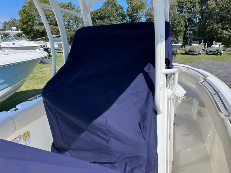 Slide: The Image of 2024 Boston Whaler 230 Outrage boat with covered seating, parked outdoors. - 32