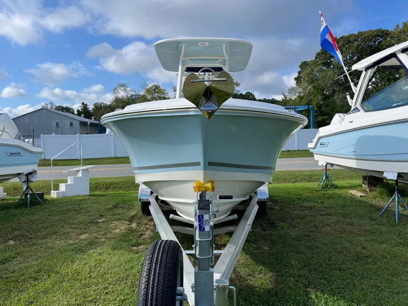 Slide: The Image of 2024 Boston Whaler 230 Outrage boat on trailer, displayed outdoors under a partly cloudy sky. - 35