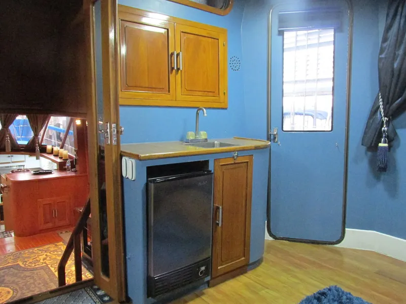 Slide: The Image of 1988 Vista 49 Motor Yacht interior with wooden cabinets, mini fridge, and blue walls. - 44