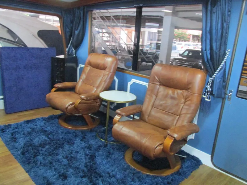 Slide: The Image of Two leather chairs in a 1988 Vista 49 Motor Yacht interior, with blue curtains and rug. - 47