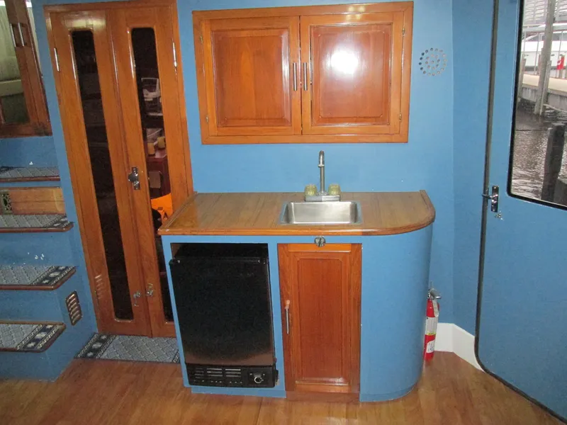 Slide: The Image of 1988 Vista 49 Motor Yacht interior with kitchenette, wooden cabinets, sink, and blue walls. - 49