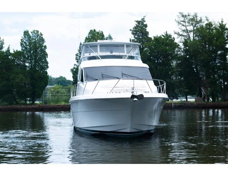 Slide: The Image of 2006 Hatteras 64 Motor Yacht on calm water, surrounded by trees. - 10