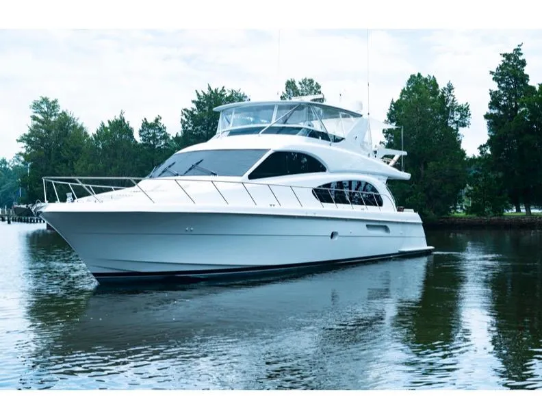 Slide: The Image of 2006 Hatteras 64 Motor Yacht on calm water, surrounded by trees. - 13