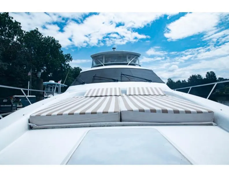 Slide: The Image of 2006 Hatteras 64 Motor Yacht with sun loungers on deck under blue sky. - 15
