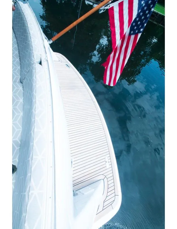 Slide: The Image of 2006 Hatteras 64 Motor Yacht with American flag, docked on calm water. - 16