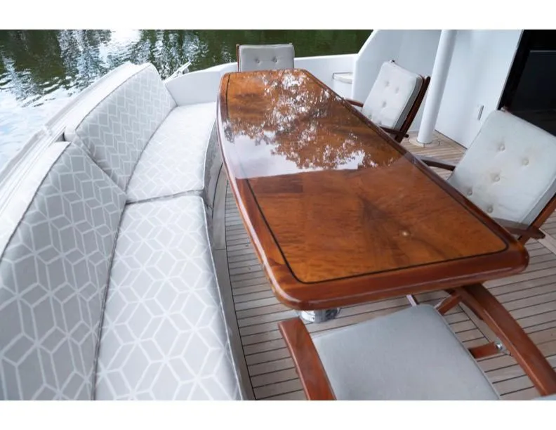 Slide: The Image of Luxurious 2006 Hatteras 64 Motor Yacht outdoor dining area with elegant wood table and cushioned seating. - 36