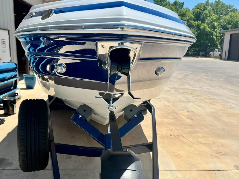 Slide: The Image of 2024 Crownline 270SS boat on trailer, blue and white hull, parked outdoors. - 18