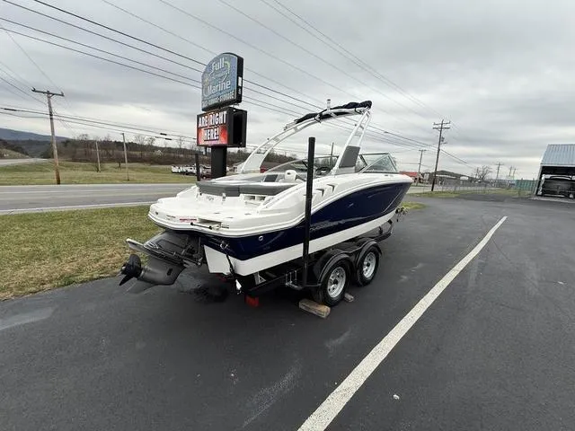 Slide: The Image of 2024 Chaparral 21 SSi boat on trailer, parked near a marine dealership. - 5