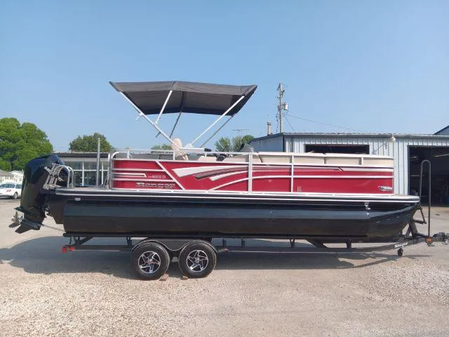 The Image of 2023 Ranger Reata 223C pontoon boat with red and black design, parked on a trailer. - 0