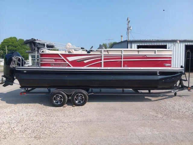 Slide: The Image of 2023 Ranger Reata 223C pontoon boat with red and black design on a trailer. - 1