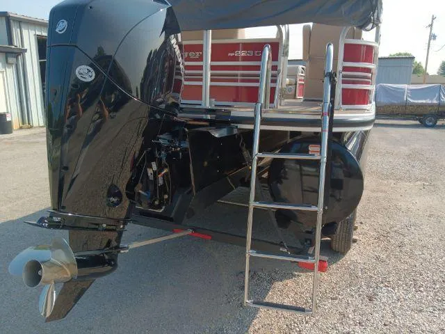 Slide: The Image of 2023 Ranger Reata 223C boat with outboard motor and ladder, parked outdoors. - 46