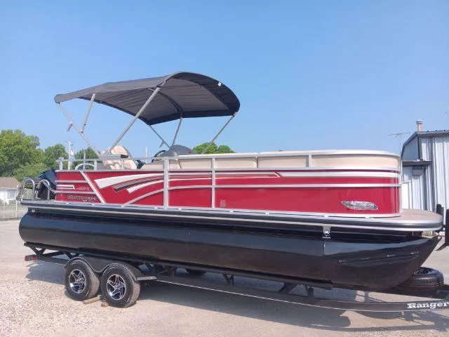 Slide: The Image of 2023 Ranger Reata 223C pontoon boat with red and black design on a trailer. - 6