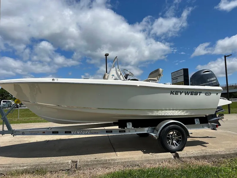 Slide: The Image of 2024 Key West 179 FS boat on a trailer under a partly cloudy sky. - 1