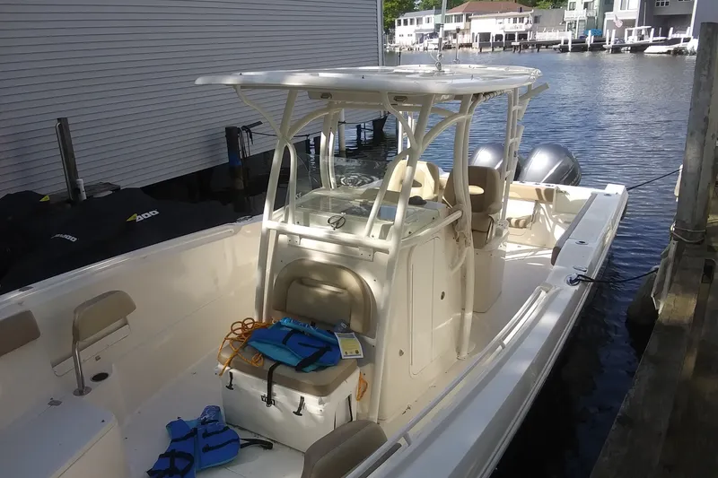 Slide: The Image of 2015 Sailfish 320 CC boat docked, featuring dual engines and life jackets on deck. - 30