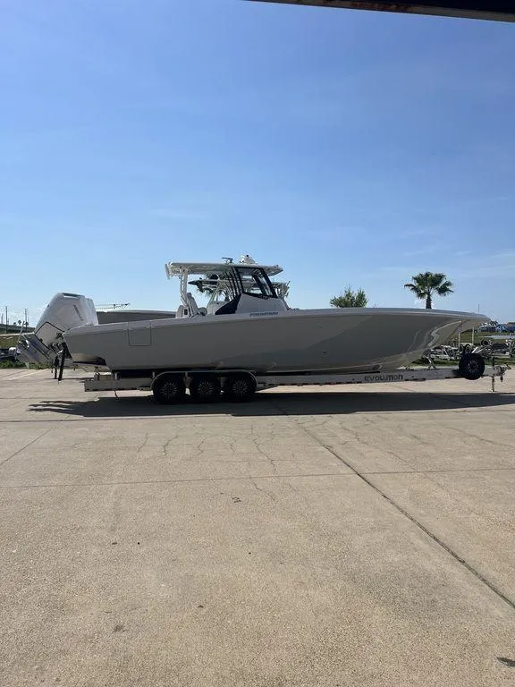 Slide: The Image of 2024 Fountain 38 TE boat on trailer, parked outdoors under clear blue sky. - 16