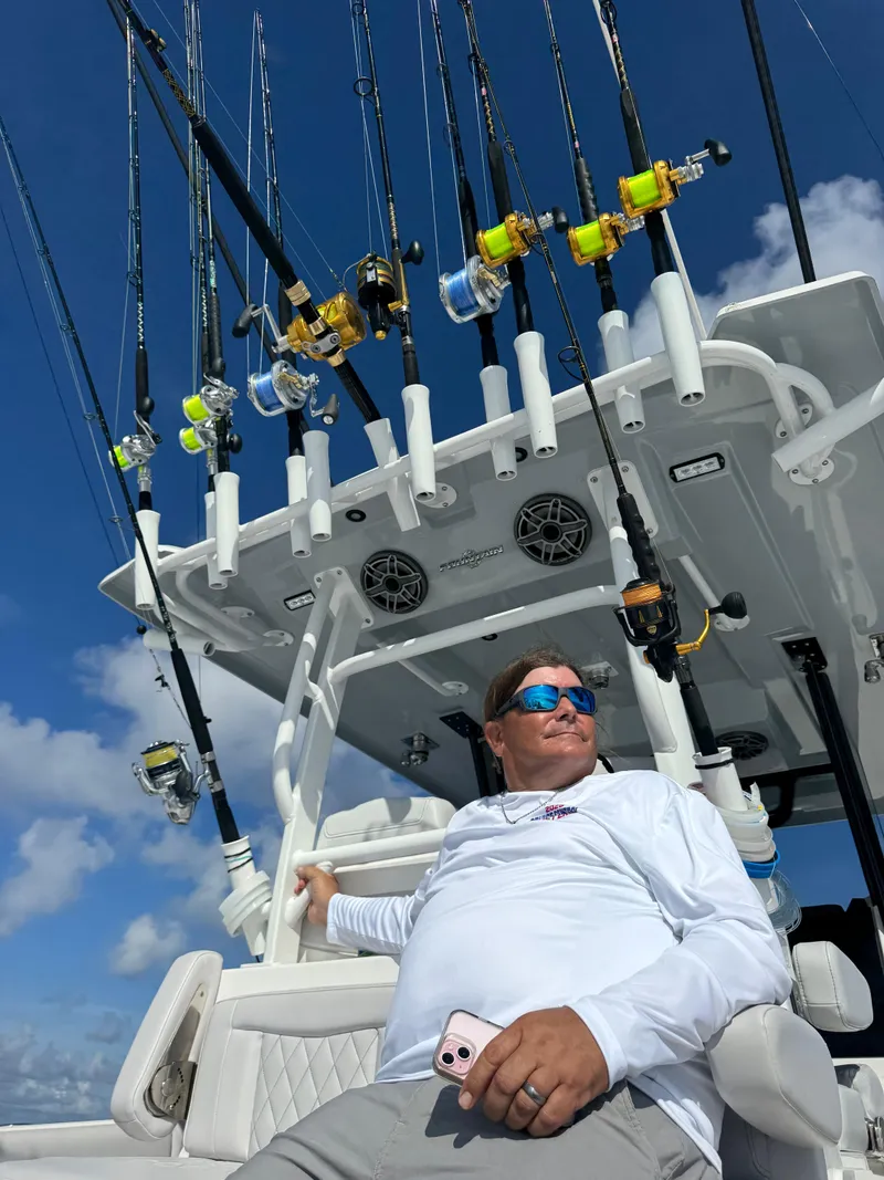Slide: The Image of Man relaxing on a 2024 Fountain 38 Tournament Edition boat with fishing rods. - 2