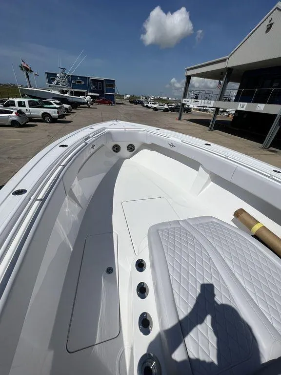 Slide: The Image of 2024 Fountain 38 TE boat, spacious deck, white interior, parked at marina under clear blue sky. - 40