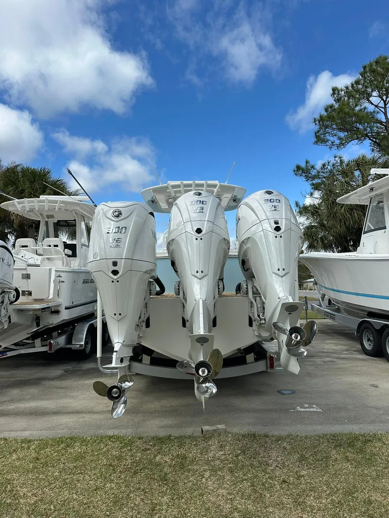 Slide: The Image of 2024 Regulator 34 boat with triple outboard engines, parked on a sunny day. - 13