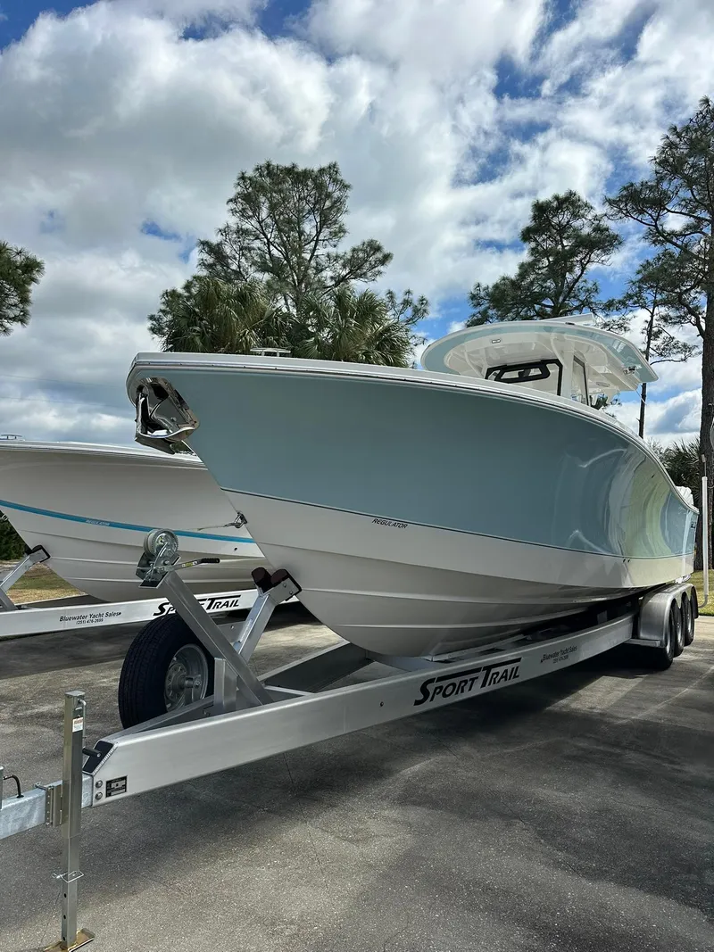 Slide: The Image of 2024 Regulator 34 boat on Sport Trak trailer under cloudy sky. - 15