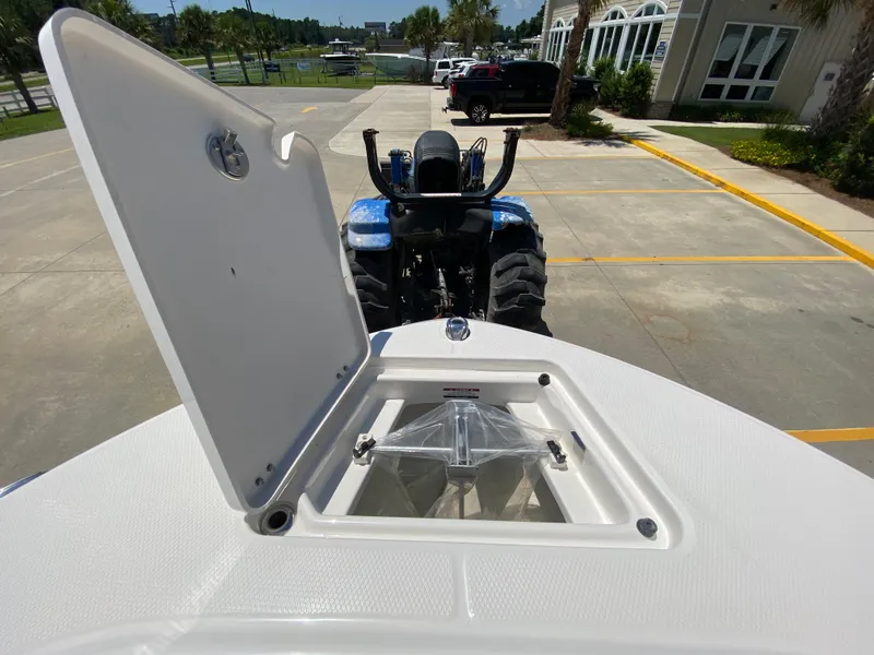 Slide: The Image of 2026 Robalo R200 Center Console boat with open storage compartment, parked near a tractor. - 20