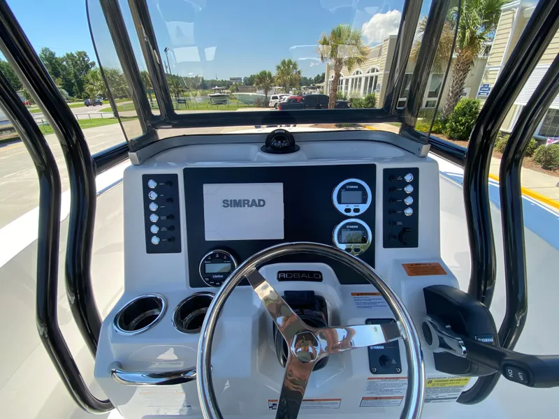 Slide: The Image of 2026 Robalo R200 Center Console boat dashboard with Simrad display and steering wheel. - 8
