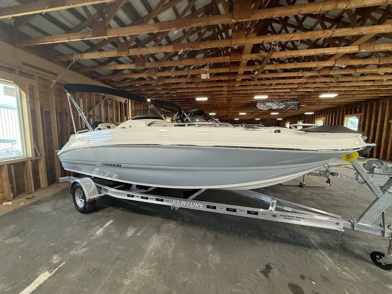 The Image of 2024 Stingray 192SC boat on trailer in wooden storage facility. - 1